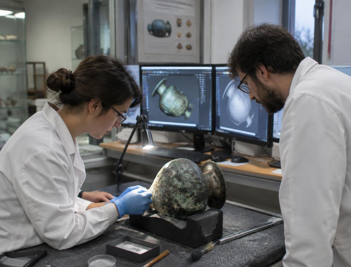 Researchers studying a recovered artefact and its 3D model